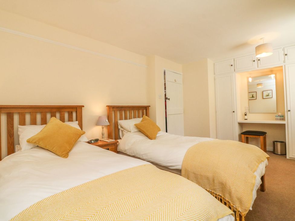A bedroom with two beds and a desk at Upper Barn Cottage in Minehead