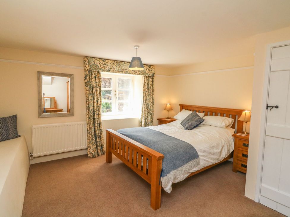 A bedroom with a bed and a window at Upper Barn Cottage Minehead