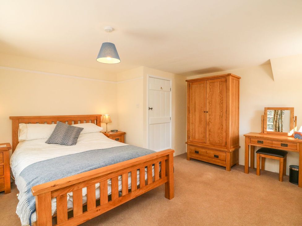 A bedroom with a bed and wooden furniture at Upper Barn Cottage Minehead
