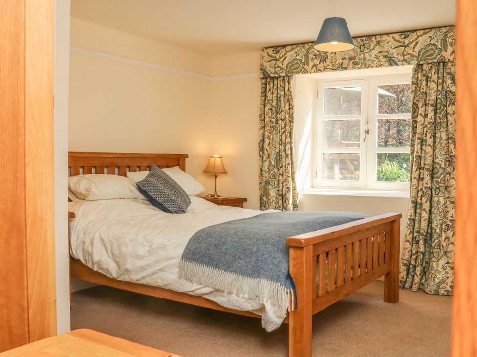 A bedroom with a wooden bed and window at Upper Barn Cottage Minehead