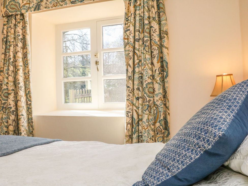A bedroom with a window and curtains at Upper Barn Cottage Minehead