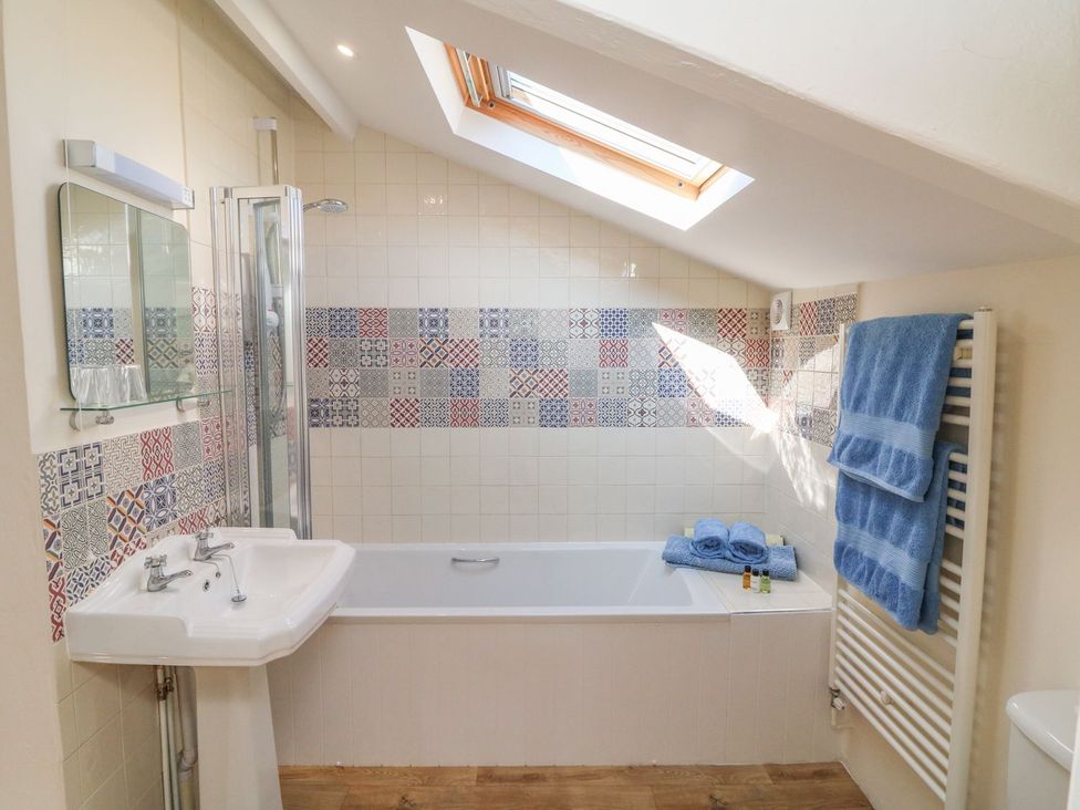 A bathroom with a bathtub and sink at Upper Barn Cottage Minehead
