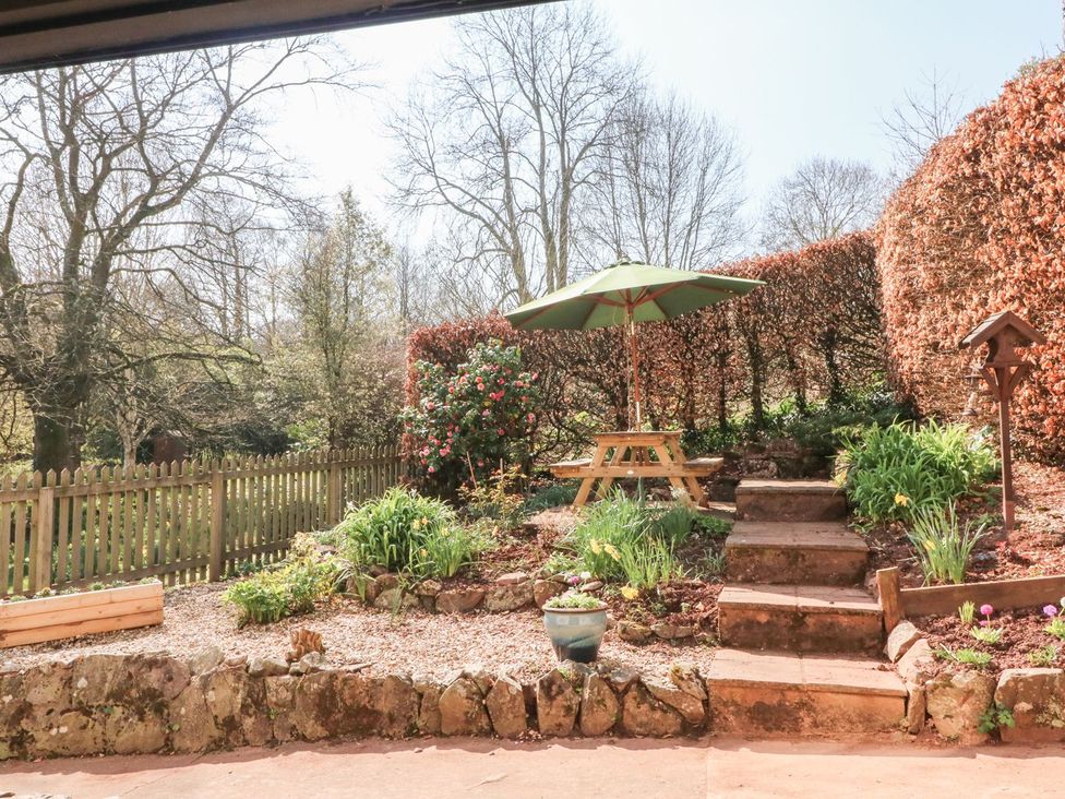 A garden with a picnic table and umbrella at Upper Barn Cottage Minehead