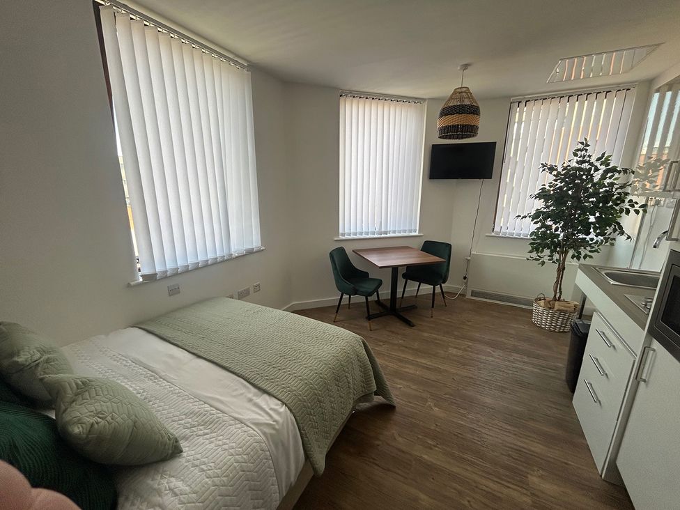 A studio with a bed, table, chairs and kitchenette at 1 Bed Studio, Sleeps 2 with City Views, Liverpool