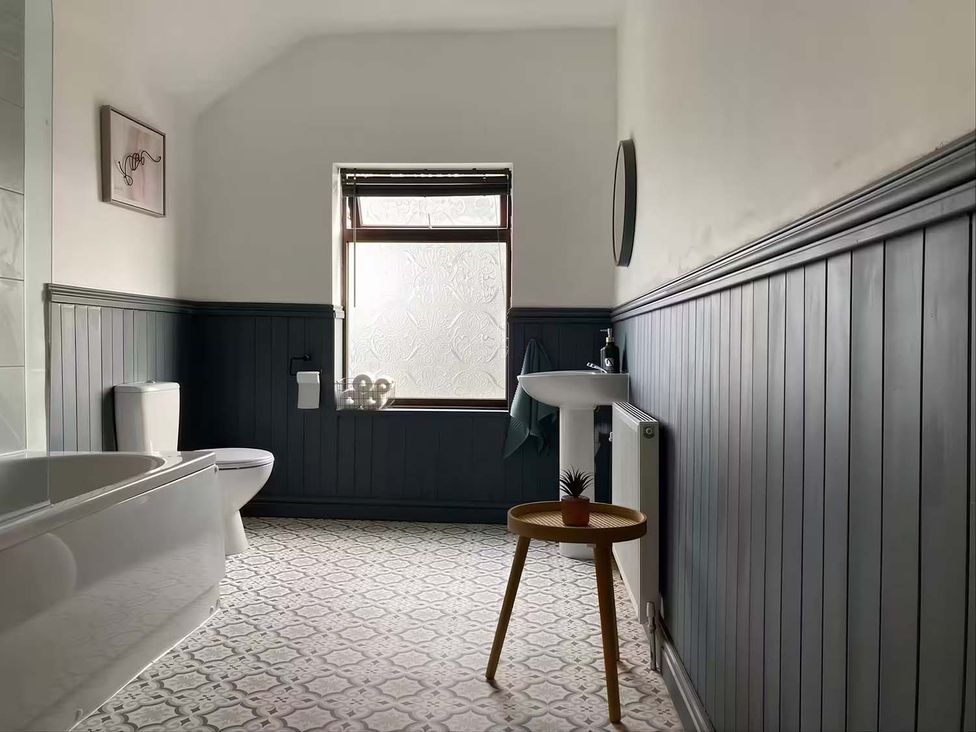 A bathroom with a toilet, bathtub, sink, and window at 2 Bed House in Creswell, Sleeps 7 with Street Parking, Creswell