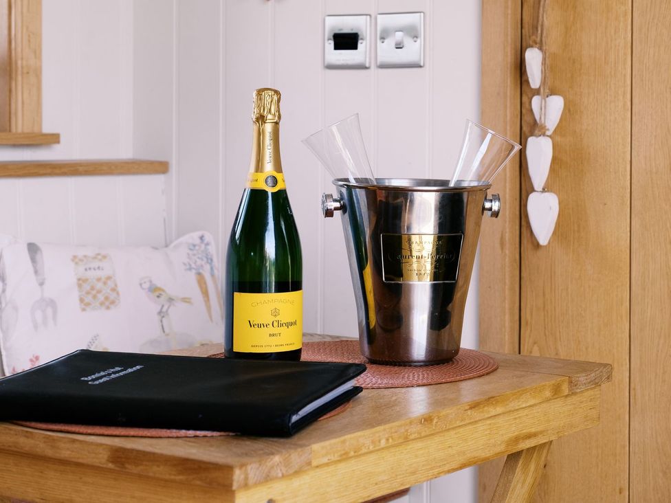A wooden table with champagne and glasses at Bonnie's Shepherds Hut at Shepherds Lodge Retreat and Wellness Nottingham