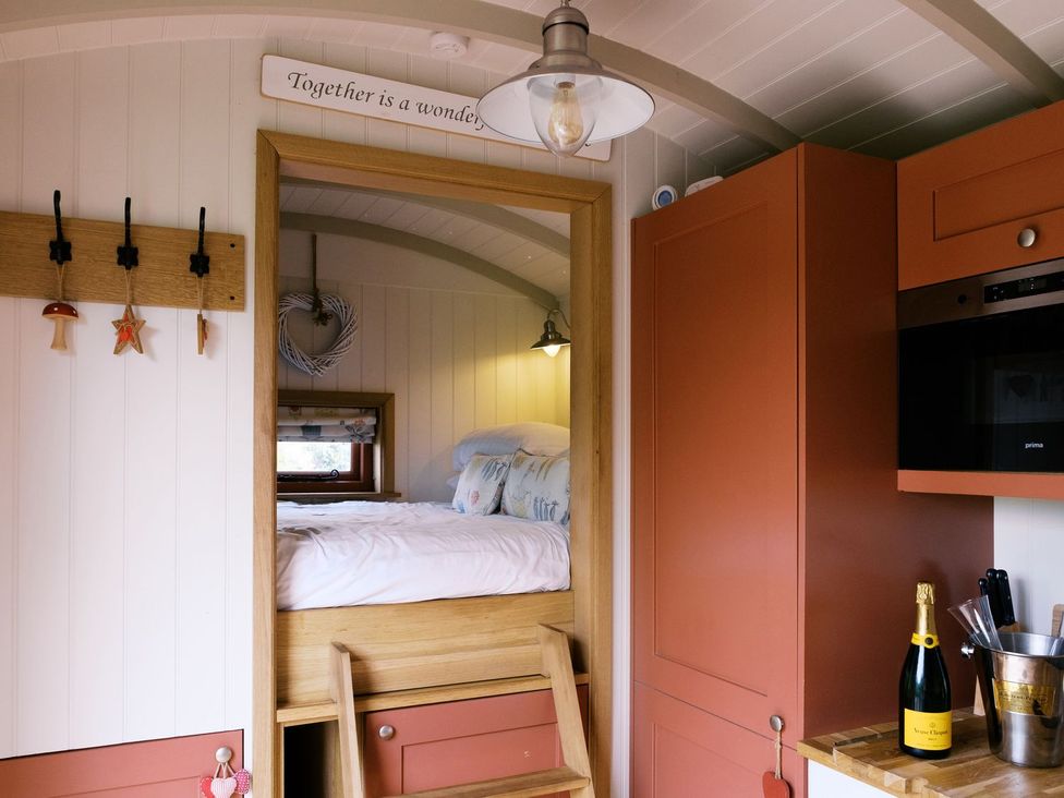 A kitchen area with bed and wine bottle at Bonnie's Shepherds Hut at Shepherds Lodge Retreat and Wellness Nottingham