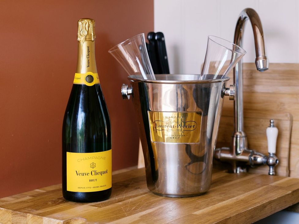 A bottle of Veuve Clicquot champagne with glasses in an ice bucket in a kitchen at Bonnie's Shepherds Hut at Shepherds Lodge Retreat and Wellness Nottingham