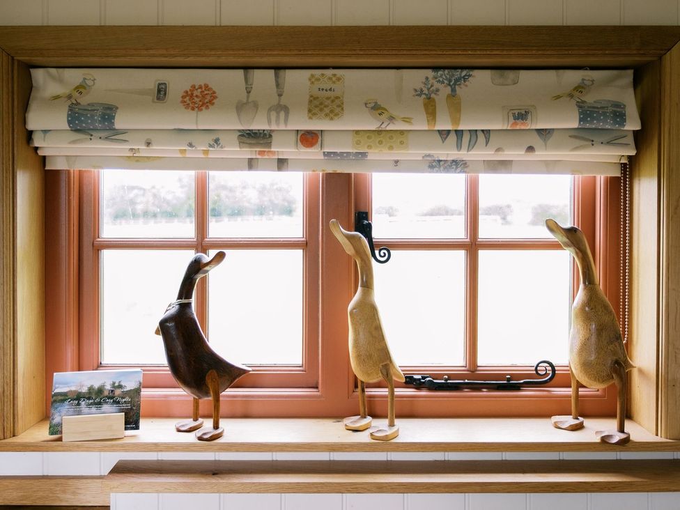 A kitchen window with wooden ducks and a decorative window treatment at Bonnie's Shepherds Hut at Shepherds Lodge Retreat and Wellness, Nottingham