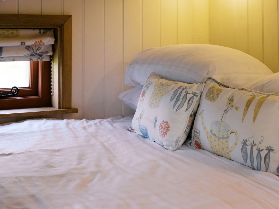 A bed with pillows and a window at Bonnie's Shepherds Hut at Shepherds Lodge Retreat and Wellness in Nottingham