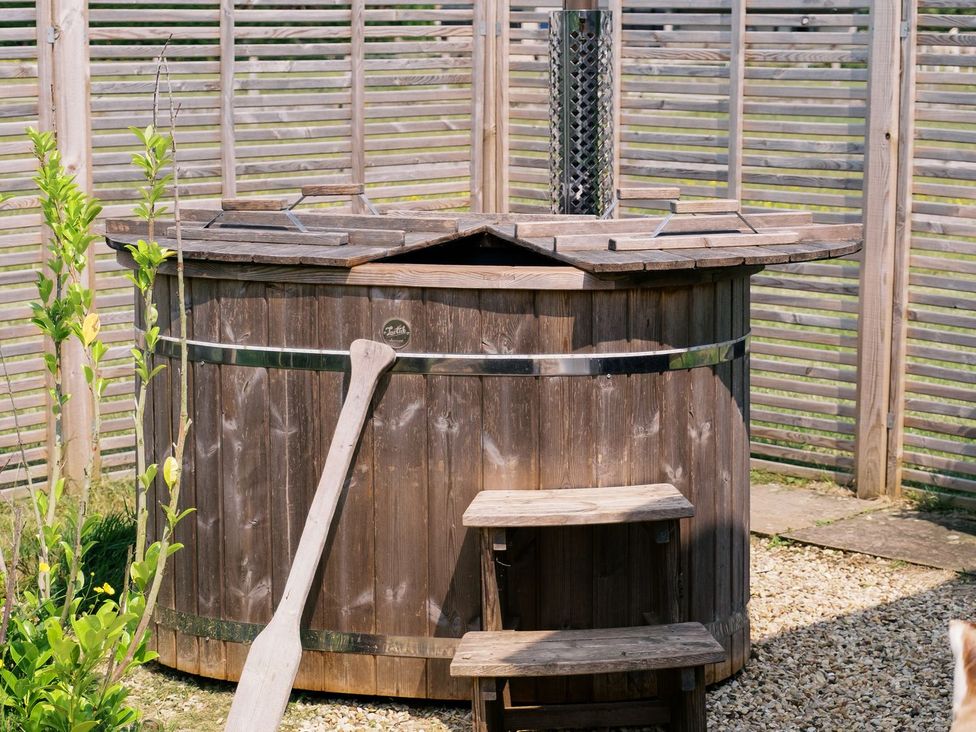 A wooden hot tub with a metal chimney in an outdoor area at Bonnie's Shepherds Hut at Shepherds Lodge Retreat and Wellness, Nottingham