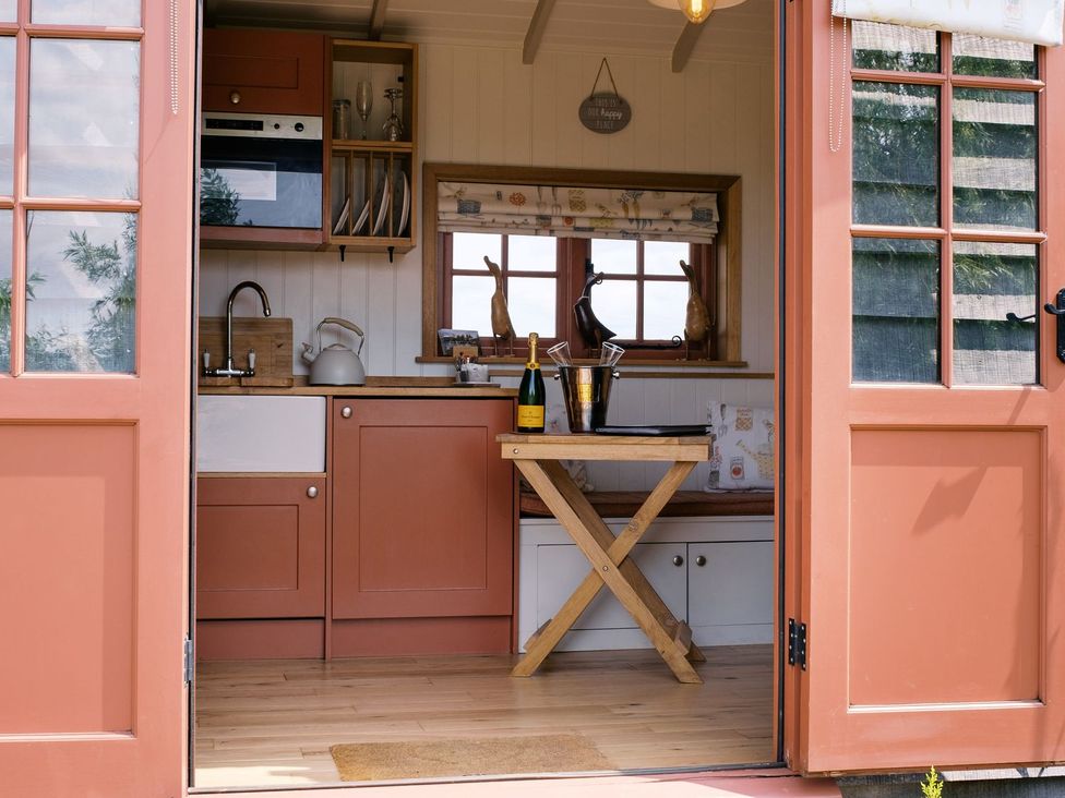 A kitchen with cabinets and a dining table at Bonnie's Shepherds Hut at Shepherds Lodge Retreat and Wellness, Nottingham
