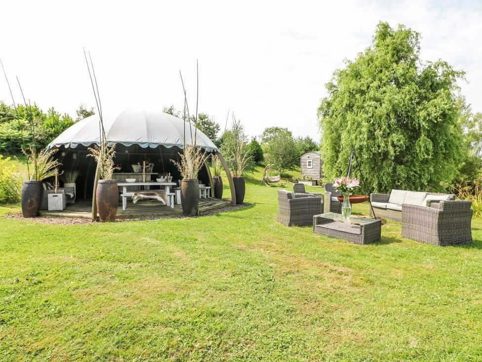 A garden with a yurt, outdoor furniture, and flower arrangements at Bonnie's Shepherds Hut at Shepherds Lodge Retreat and Wellness, Nottingham
