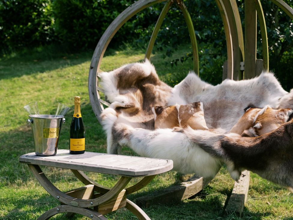 A wooden table with champagne and a bucket in a garden at Bonnie's Shepherds Hut at Shepherds Lodge Retreat and Wellness Nottingham