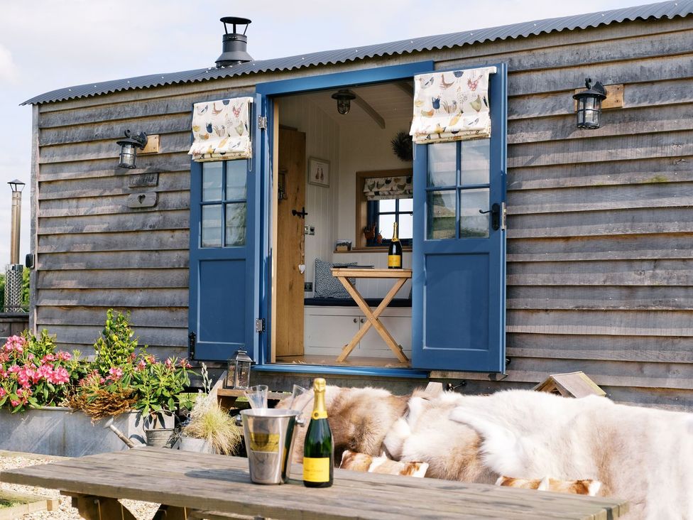 An outdoor area with a blue door and a table at Lillie's Shepherds Hut at Shepherds Lodge Retreat and Wellness, Nottingham