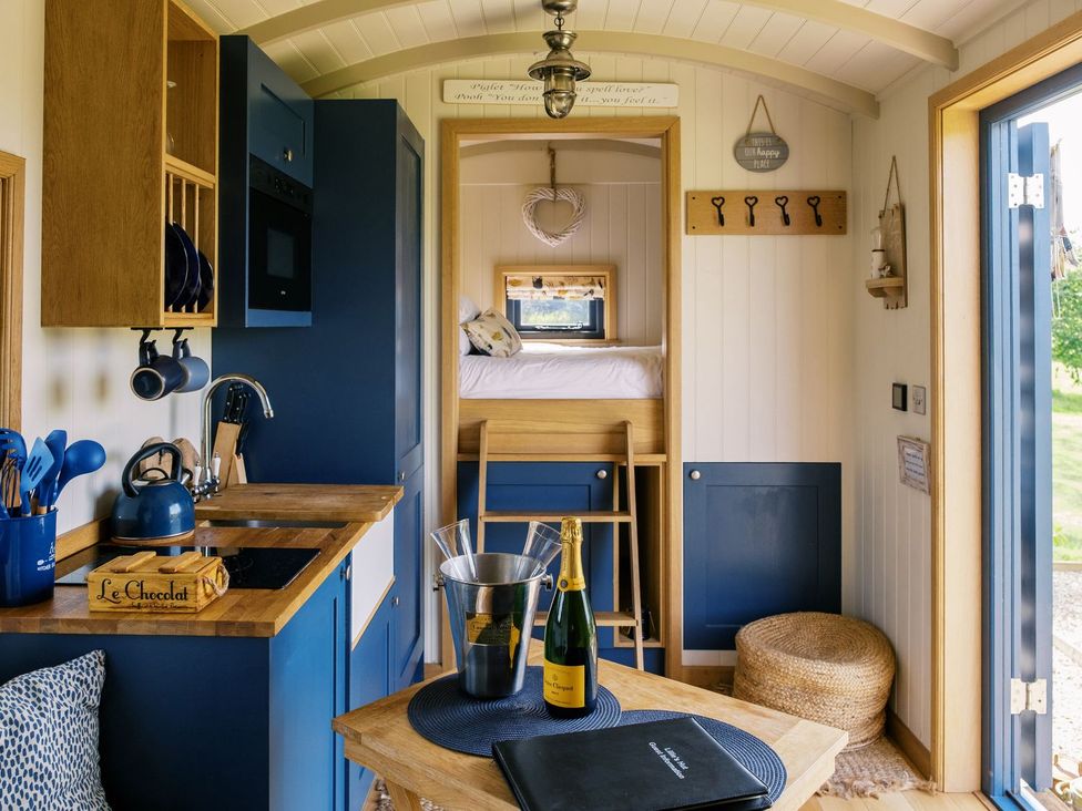 A kitchen area with a stove and a bed at Lillie's Shepherds Hut at Shepherds Lodge Retreat and Wellness Nottingham