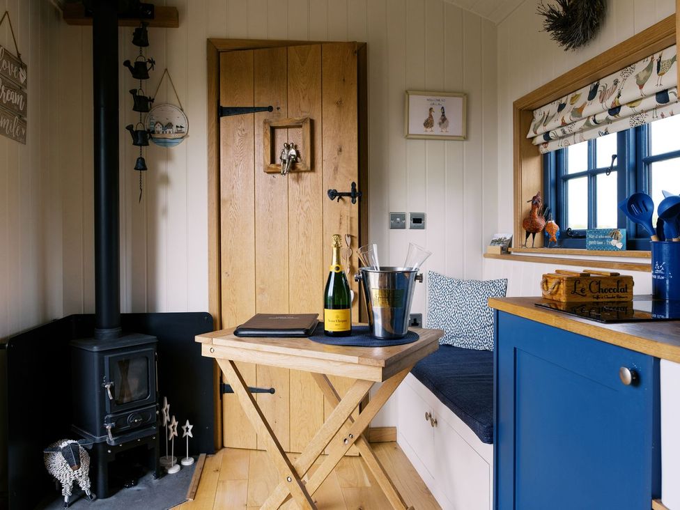 A kitchen with a wooden table and champagne at Lillie's Shepherds Hut at Shepherds Lodge Retreat and Wellness Nottingham
