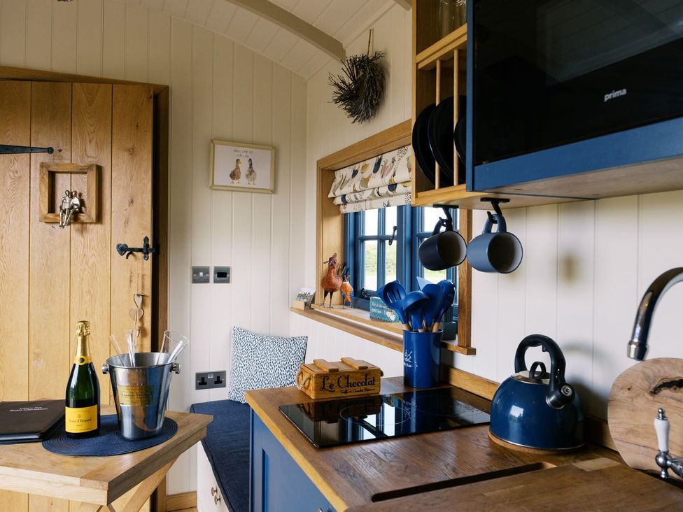 A kitchen with a cooking stove and a window at Lillie's Shepherds Hut at Shepherds Lodge Retreat and Wellness Nottingham