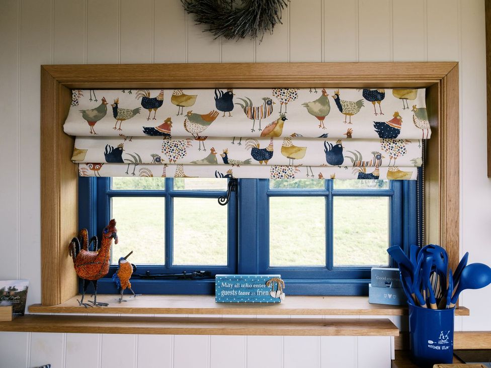 A kitchen window with decorative curtain and utensils at Lillie's Shepherds Hut at Shepherds Lodge Retreat and Wellness Nottingham