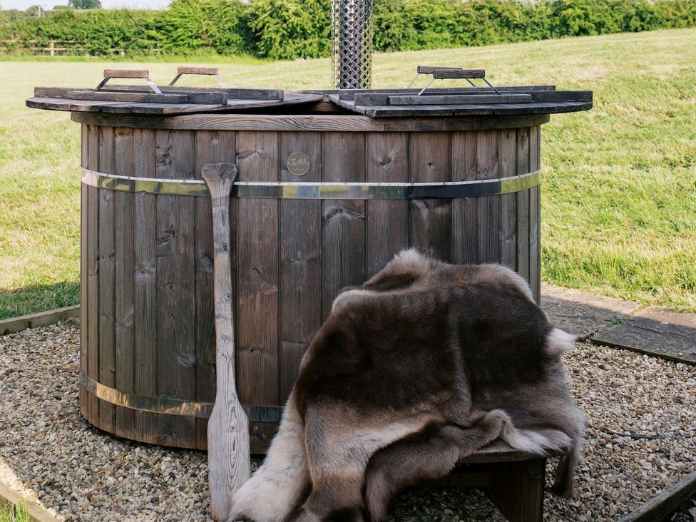 A wooden hot tub with a paddle and fur blanket at Lillie's Shepherds Hut at Shepherds Lodge Retreat and Wellness Nottingham
