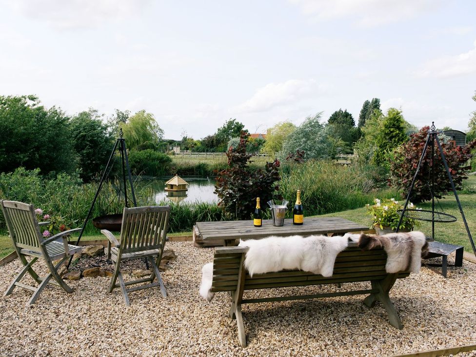 A garden with a table and chairs near a pond at Lillie's Shepherds Hut at Shepherds Lodge Retreat and Wellness Nottingham