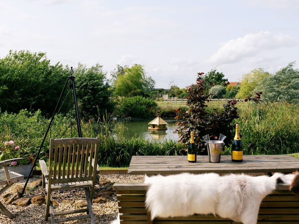 An outdoor area with a table and chairs near a lake at Lillie's Shepherds Hut at Shepherds Lodge Retreat and Wellness, Nottingham
