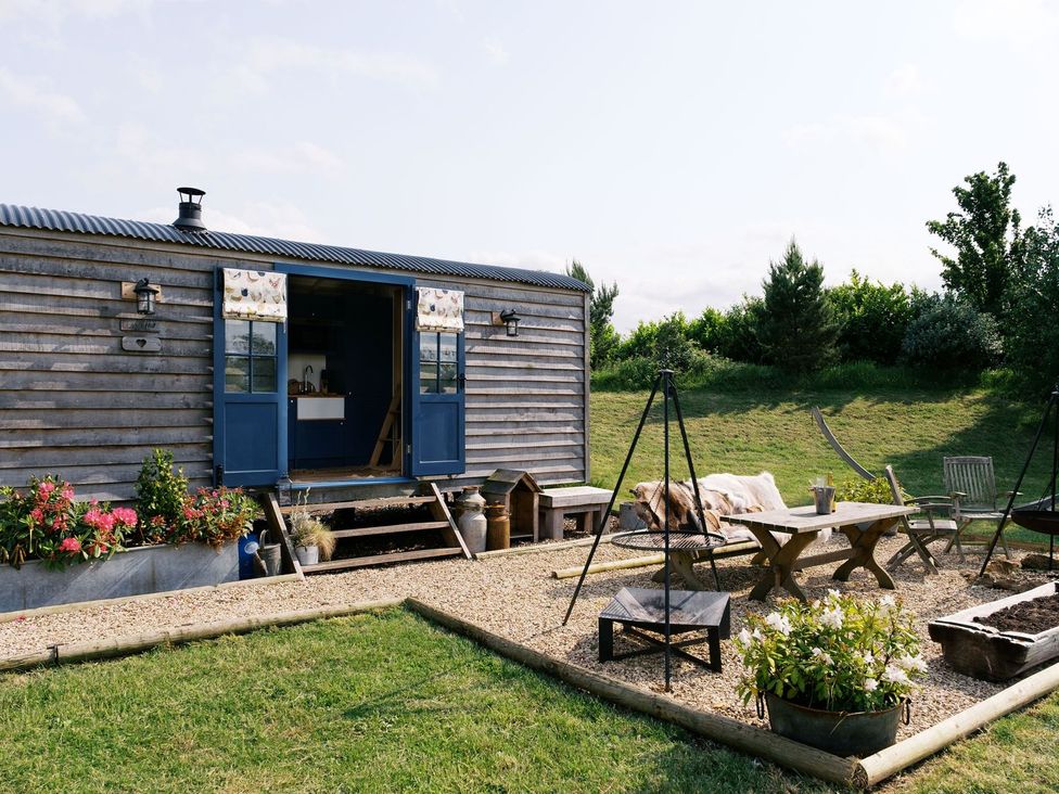 A garden with a wooden cabin and outdoor seating at Lillie's Shepherds Hut at Shepherds Lodge Retreat and Wellness Nottingham