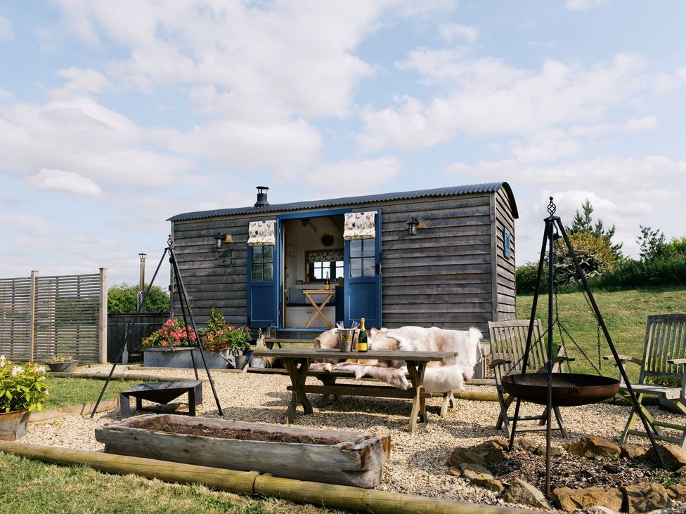 A hut with a table and chairs outside at Lillie's Shepherds Hut at Shepherds Lodge Retreat and Wellness Nottingham