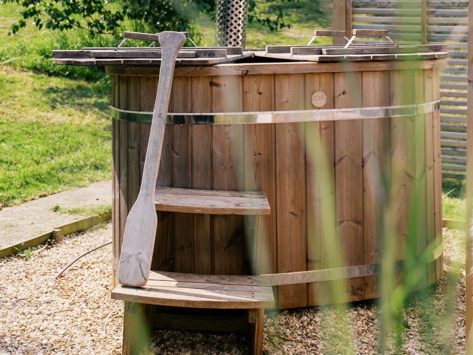 A hot tub with wooden steps and paddle in an outdoor area at Lillie's Shepherds Hut at Shepherds Lodge Retreat and Wellness Nottingham