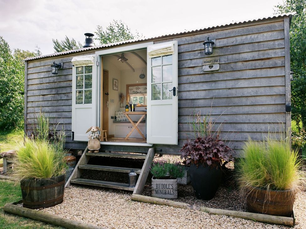 A shepherd's hut with an open door and plants outside at Herbie's Shepherds Hut at Shepherds Lodge Retreat and Wellness Nottingham