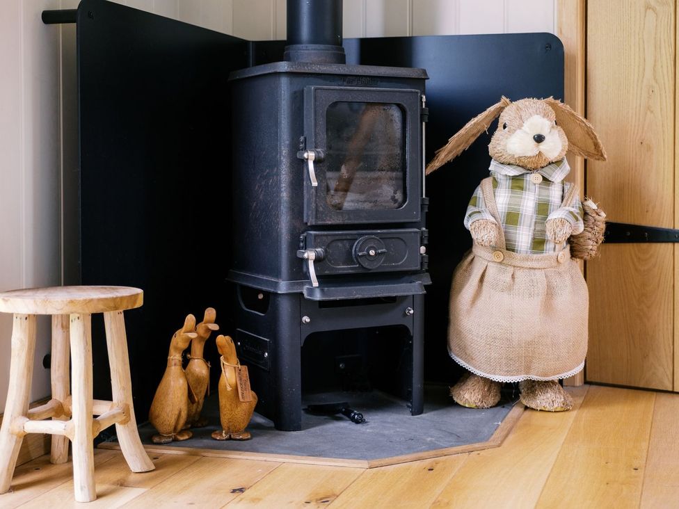 A living room with a wood stove and a stuffed animal at Herbie's Shepherds Hut at Shepherds Lodge Retreat and Wellness Nottingham