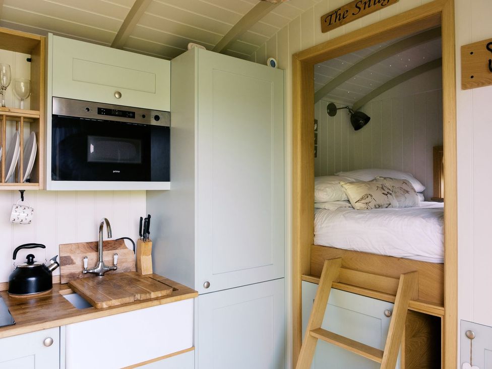 A kitchen with cabinets, sink, and a bed in a loft at Herbie's Shepherds Hut at Shepherds Lodge Retreat and Wellness Nottingham