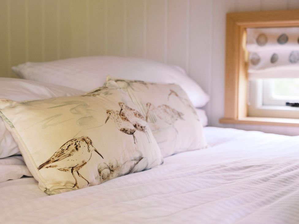 A bed with patterned pillows and a window at Herbie's Shepherds Hut at Shepherds Lodge Retreat and Wellness Nottingham