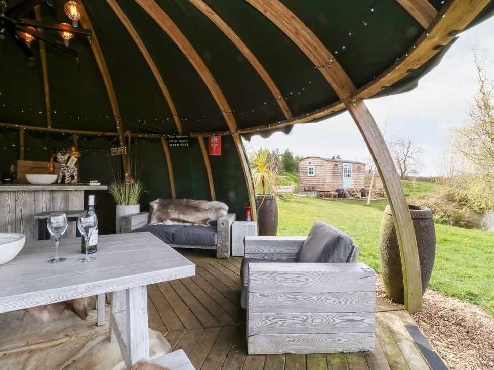 An outdoor seating area with a table and drinks at Herbie's Shepherds Hut at Shepherds Lodge Retreat and Wellness Nottingham