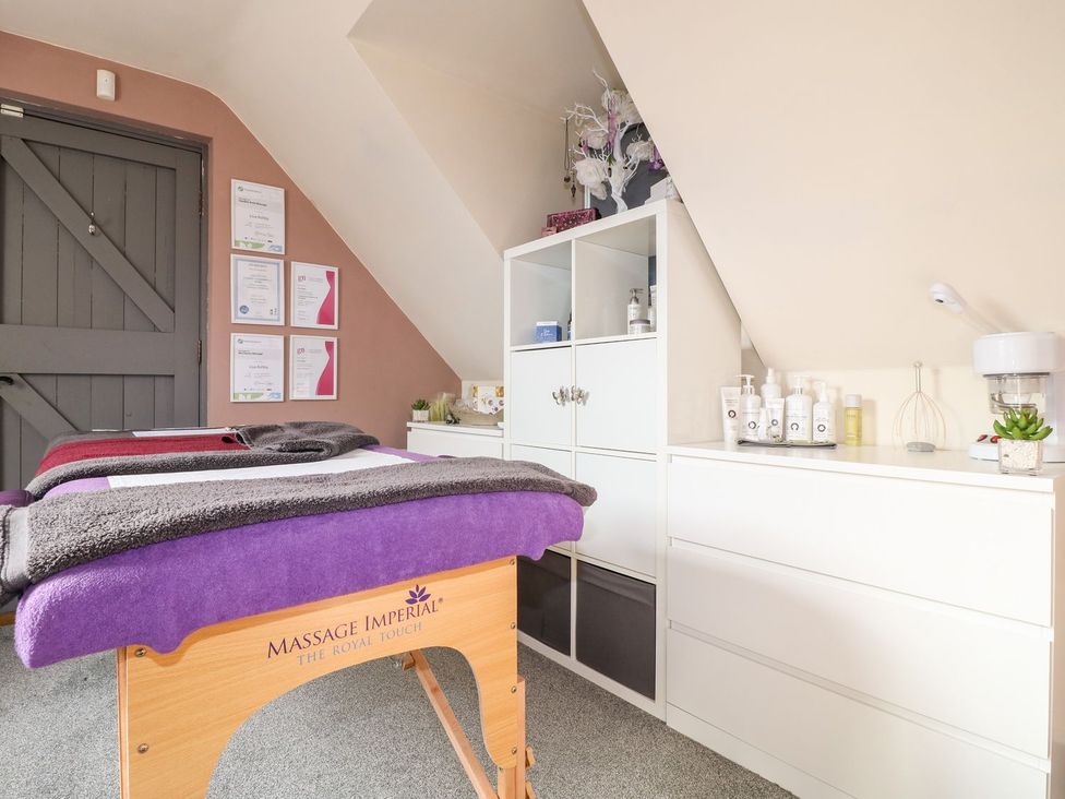 A treatment room with a massage table and shelves at Herbie's Shepherds Hut at Shepherds Lodge Retreat and Wellness, Nottingham