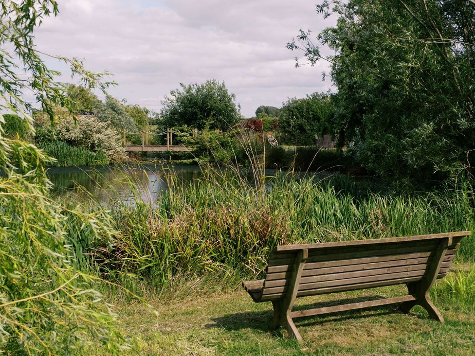 A bench overlooking a pond and bridge at Herbie's Shepherds Hut at Shepherds Lodge Retreat and Wellness Nottingham