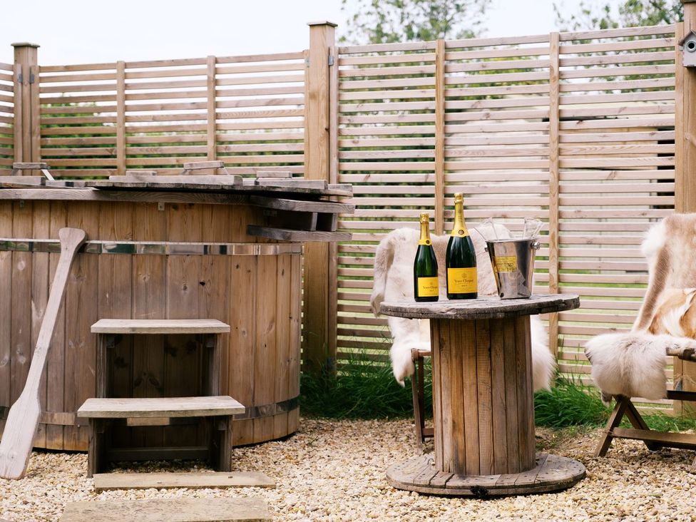 An outdoor area with a hot tub and champagne bottles at Poppie's Shepherds Hut at Shepherds Lodge Retreat and Wellness, Nottingham