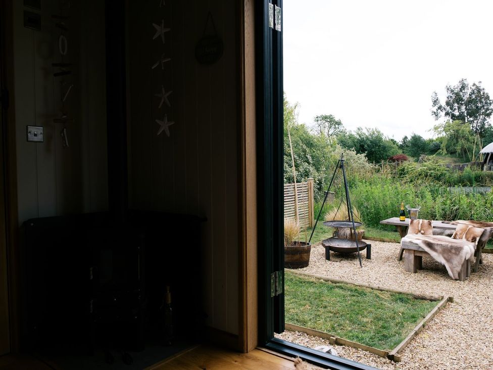 A view from a door to an outdoor seating area at Poppie's Shepherds Hut at Shepherds Lodge Retreat and Wellness, Nottingham