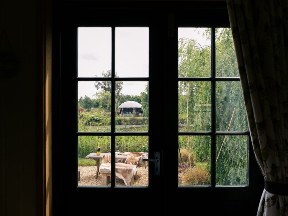 A view of a garden with a table and chairs from an indoor window at Poppie's Shepherds Hut at Shepherds Lodge Retreat and Wellness Nottingham