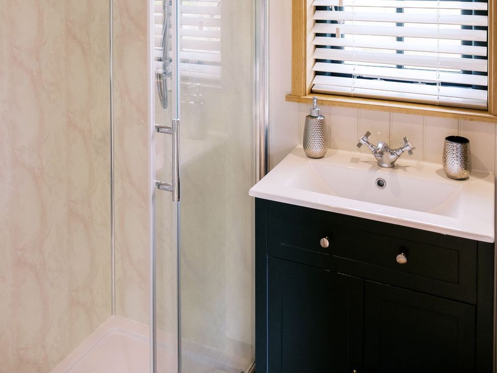 A bathroom with a shower and sink at Poppie's Shepherds Hut at Shepherds Lodge Retreat and Wellness Nottingham