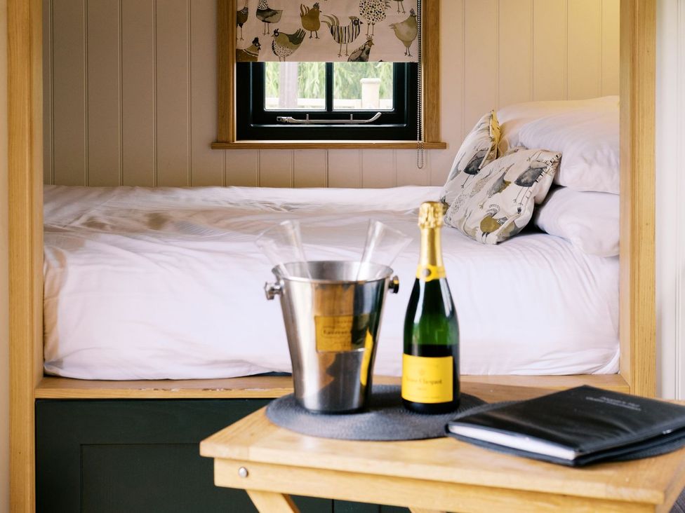 A bedroom with a bed and champagne bottle at Poppie's Shepherds Hut at Shepherds Lodge Retreat and Wellness, Nottingham