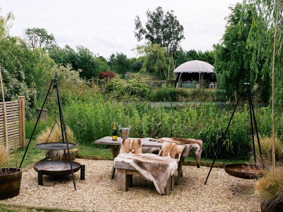 A garden with seating, fire pits, and a bottle of champagne at Poppie's Shepherds Hut at Shepherds Lodge Retreat and Wellness in Nottingham