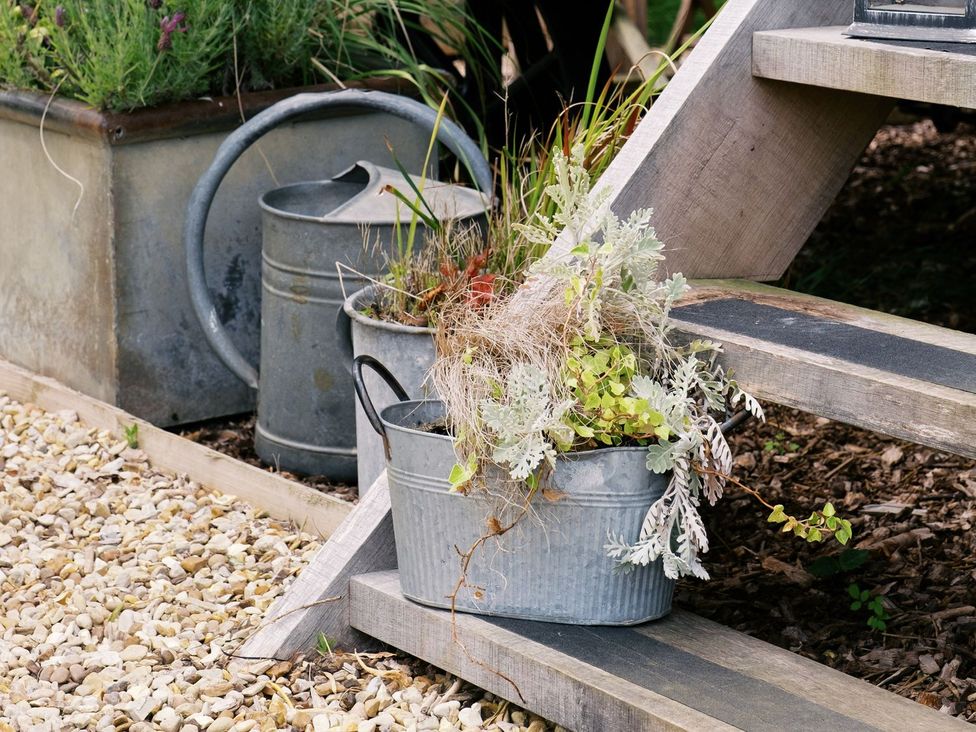 A planter and watering can on wooden steps at Poppie's Shepherds Hut at Shepherds Lodge Retreat and Wellness, Nottingham