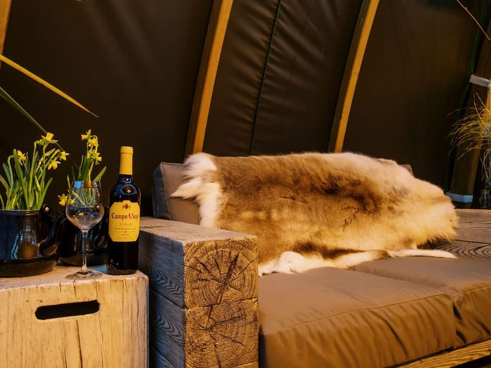 A sitting area with a sofa, wine and flowers at Poppie's Shepherds Hut at Shepherds Lodge Retreat and Wellness Nottingham