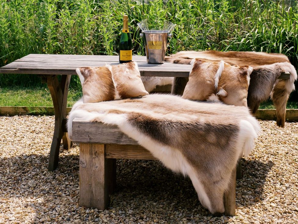 An outdoor setting with a wooden table and champagne at Poppie's Shepherds Hut at Shepherds Lodge Retreat and Wellness Nottingham