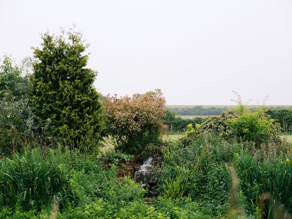 A garden with trees and a small waterfall at Poppie's Shepherds Hut at Shepherds Lodge Retreat and Wellness Nottingham