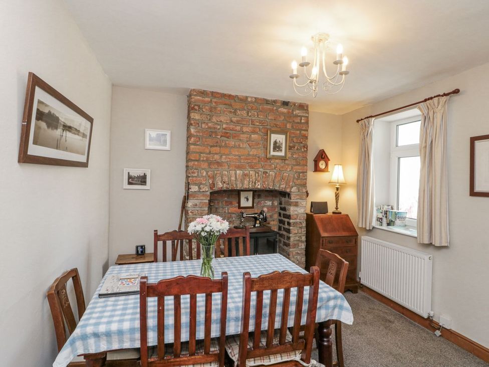 A dining room with a brick fireplace and wooden furniture at Chapel Cottage in Filey