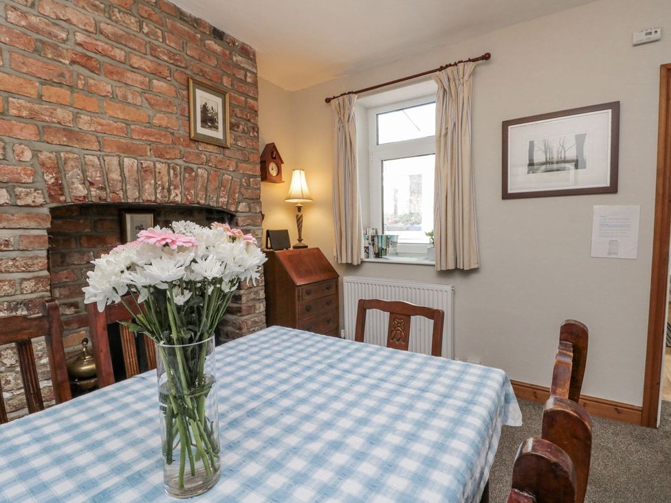 A dining room with a table and flowers at Chapel Cottage in Filey