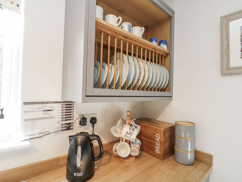 A kitchen with a kettle, plates on a rack, and a storage box at Chapel Cottage in Filey