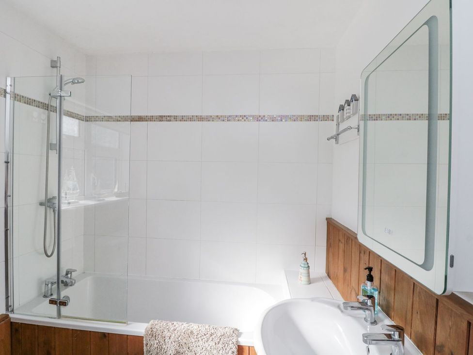 A bathroom with a bathtub, shower, and sink at Chapel Cottage in Filey